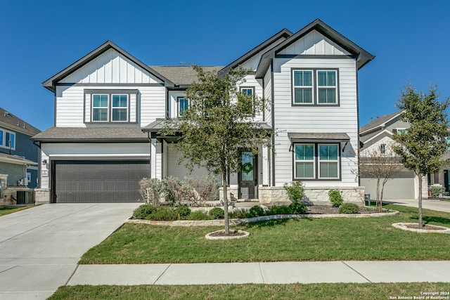 craftsman-style house featuring a garage, central AC unit, and a front yard