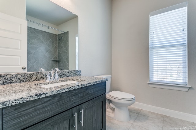 bathroom featuring vanity, tile patterned floors, toilet, and a tile shower