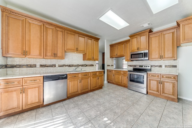 kitchen with light tile patterned floors, sink, decorative backsplash, and appliances with stainless steel finishes