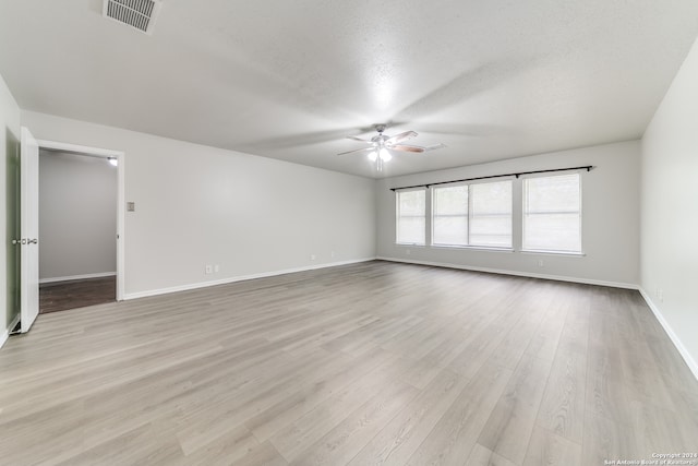 spare room with ceiling fan, a textured ceiling, and light wood-type flooring