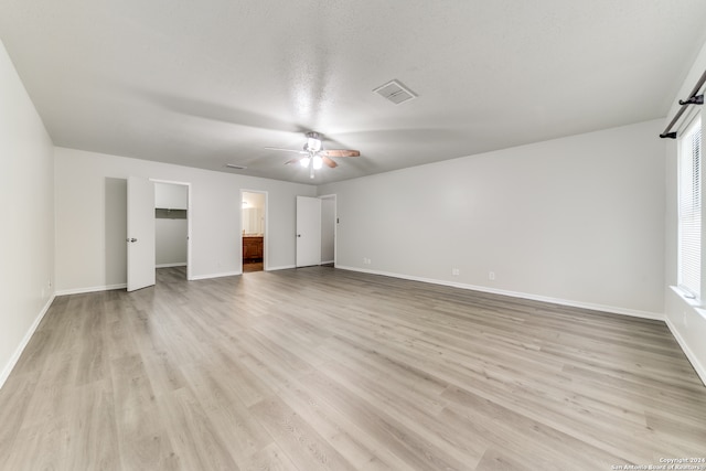 unfurnished bedroom with light wood-type flooring, a textured ceiling, ceiling fan, and ensuite bath