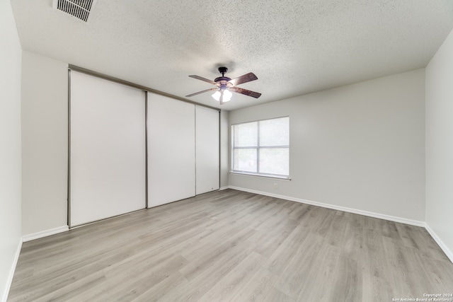 unfurnished bedroom with light hardwood / wood-style flooring, a textured ceiling, ceiling fan, and a closet