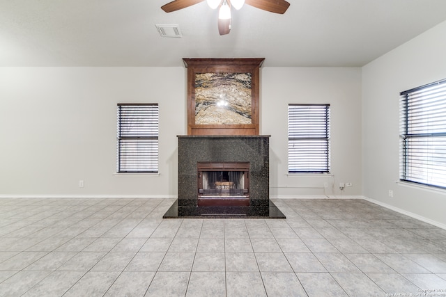 unfurnished living room featuring light tile patterned floors, ceiling fan, and a fireplace