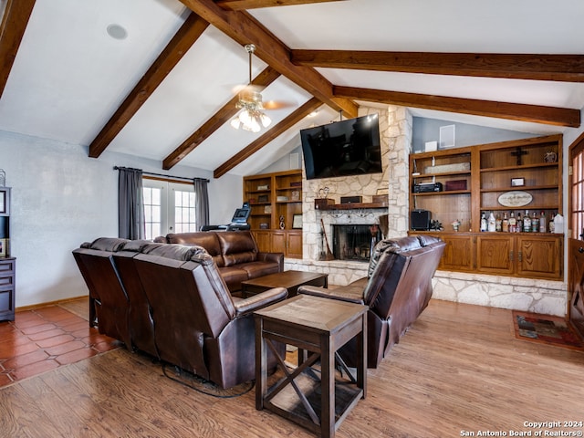 living room with a stone fireplace, french doors, vaulted ceiling with beams, ceiling fan, and light wood-type flooring