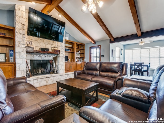 living room featuring a stone fireplace, beamed ceiling, wood-type flooring, and ceiling fan