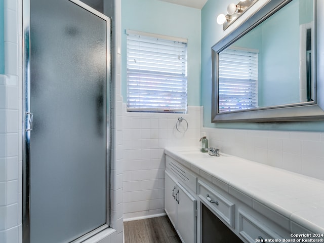 bathroom with tile walls, walk in shower, vanity, and hardwood / wood-style flooring