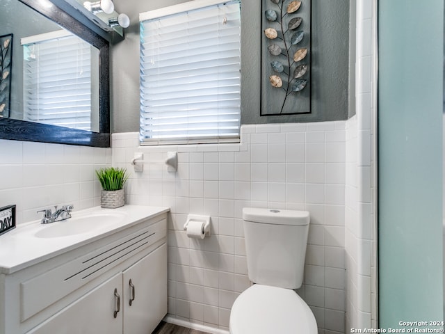 bathroom featuring tile walls, plenty of natural light, vanity, and toilet