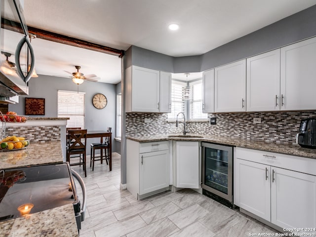 kitchen with stainless steel appliances, white cabinetry, stone counters, decorative backsplash, and beverage cooler