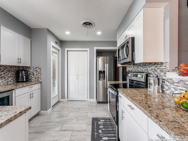 kitchen featuring white cabinetry, appliances with stainless steel finishes, decorative backsplash, and light stone counters