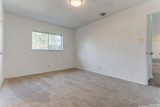 carpeted spare room featuring a textured ceiling