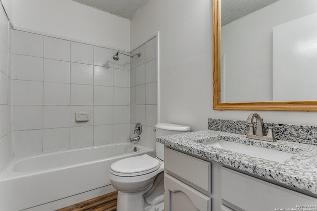 full bathroom featuring hardwood / wood-style floors, vanity, a textured ceiling, and tiled shower / bath