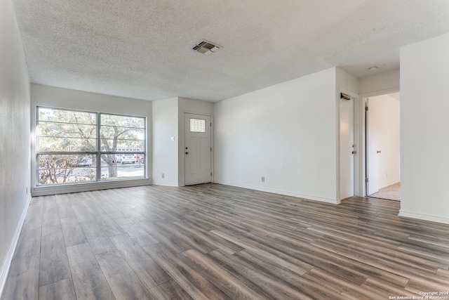 empty room with a textured ceiling and dark hardwood / wood-style floors