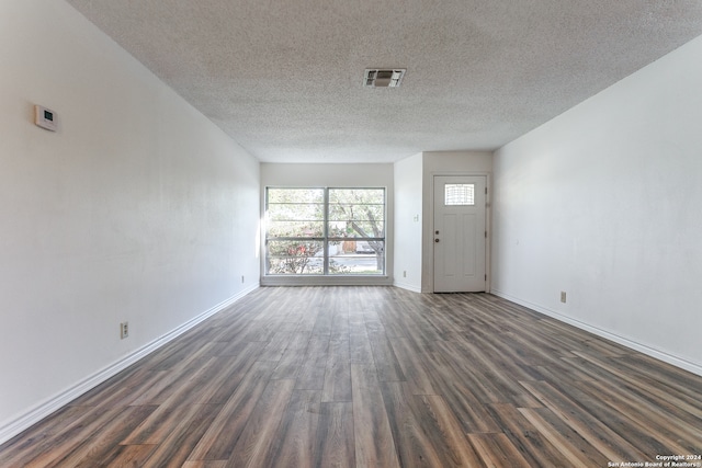 unfurnished living room with a textured ceiling and dark hardwood / wood-style flooring