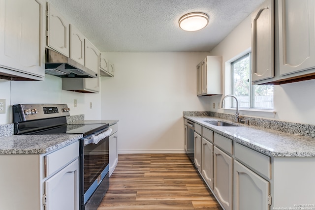 kitchen featuring appliances with stainless steel finishes, a textured ceiling, sink, light hardwood / wood-style floors, and white cabinets