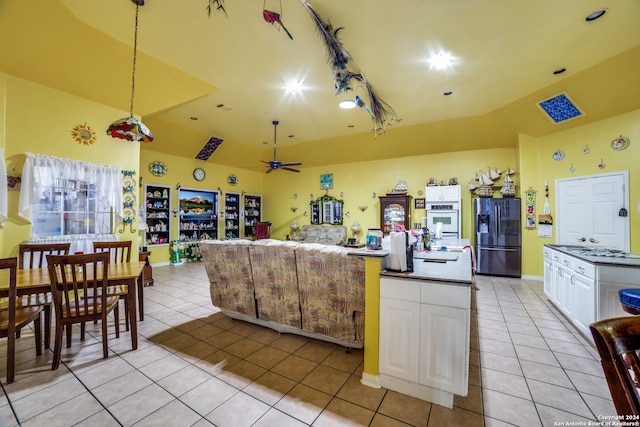 kitchen featuring stainless steel fridge with ice dispenser, light tile patterned flooring, oven, a kitchen island, and white cabinets