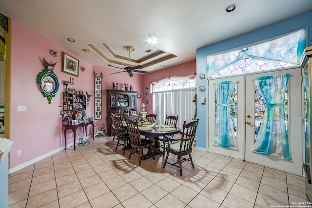 tiled dining space featuring french doors, ceiling fan, and a raised ceiling