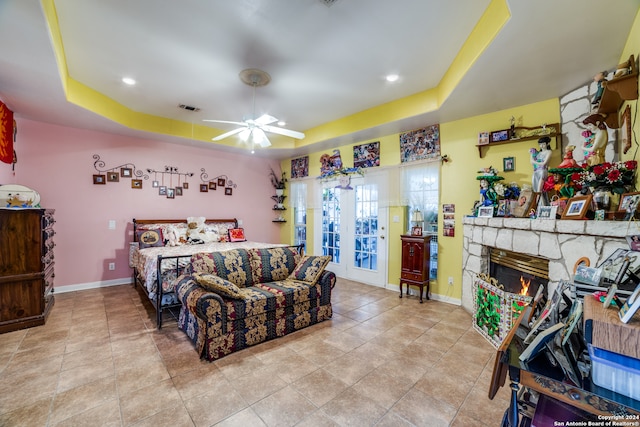 bedroom with a raised ceiling, ceiling fan, access to outside, and a fireplace