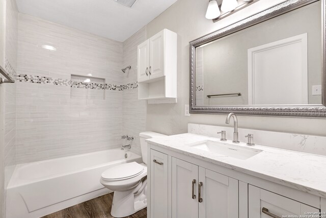 full bathroom featuring toilet, vanity, tiled shower / bath, and wood-type flooring