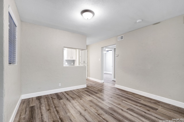 unfurnished room with light hardwood / wood-style flooring and a textured ceiling