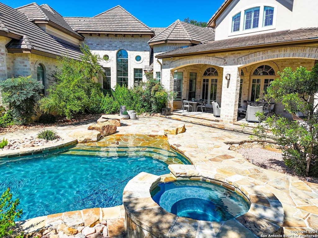 view of pool featuring an in ground hot tub and a patio area