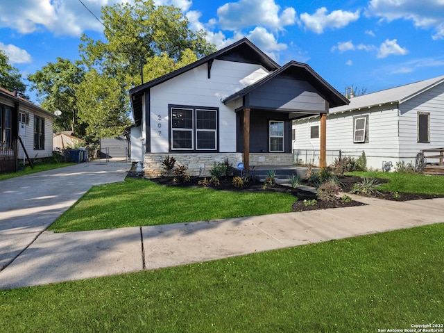 207 Ray Ave, San Antonio, TX 78204 - view of front of home with covered porch, a front yard, stone siding, and concrete driveway