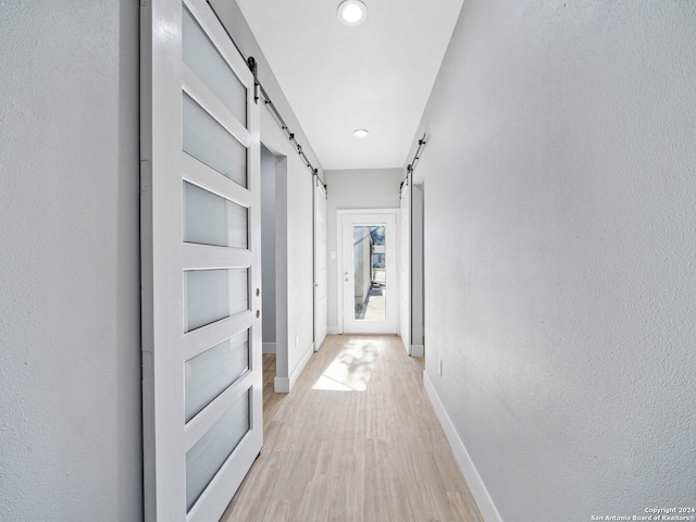 hall with light hardwood / wood-style floors and a barn door