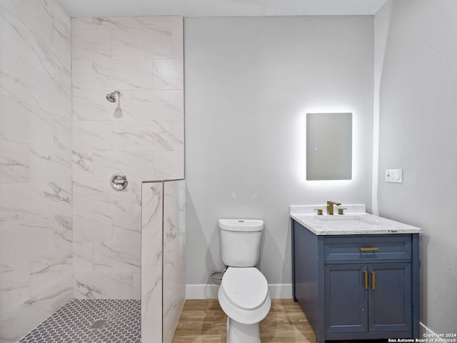 bathroom with vanity, toilet, and a tile shower