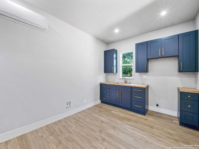 kitchen featuring butcher block countertops, light wood-type flooring, sink, blue cabinets, and a wall unit AC