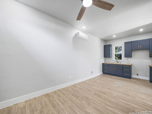 kitchen with an AC wall unit, ceiling fan, sink, and light hardwood / wood-style floors