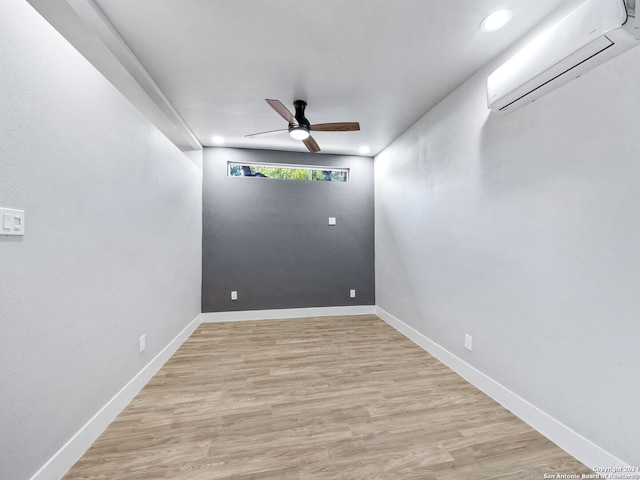 empty room featuring light hardwood / wood-style floors, ceiling fan, and an AC wall unit