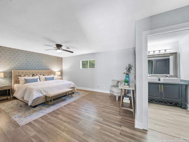 bedroom featuring ceiling fan, sink, and light hardwood / wood-style flooring