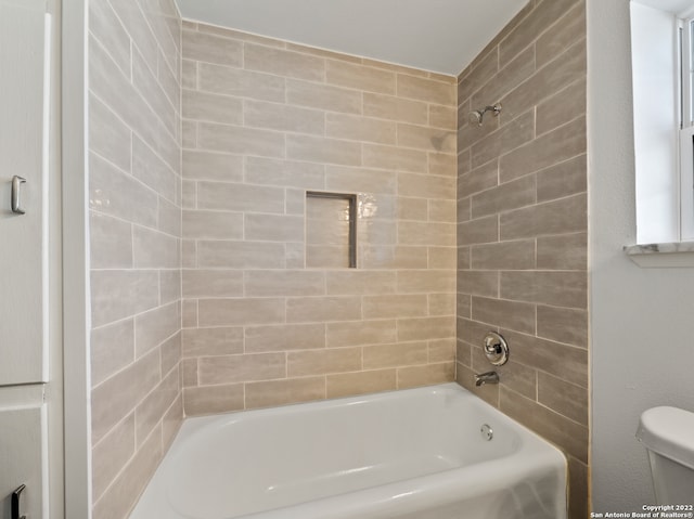 bathroom with toilet and tiled shower / bath combo