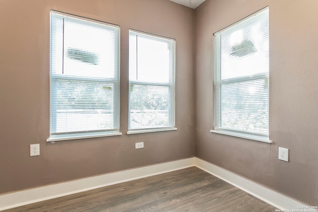 empty room with a wealth of natural light and dark hardwood / wood-style floors