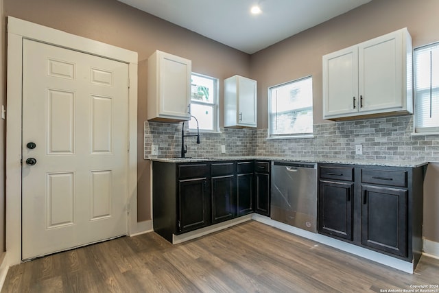 kitchen with stainless steel dishwasher, light stone countertops, white cabinetry, and hardwood / wood-style floors