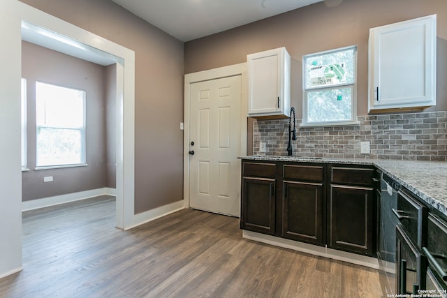 kitchen with plenty of natural light, light stone countertops, sink, and white cabinets