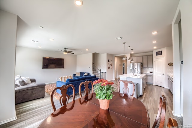 dining room featuring ceiling fan, sink, and light wood-type flooring