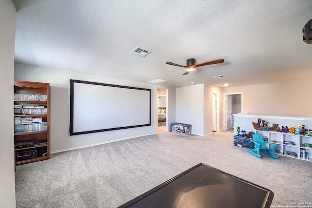 carpeted home theater with a textured ceiling and ceiling fan