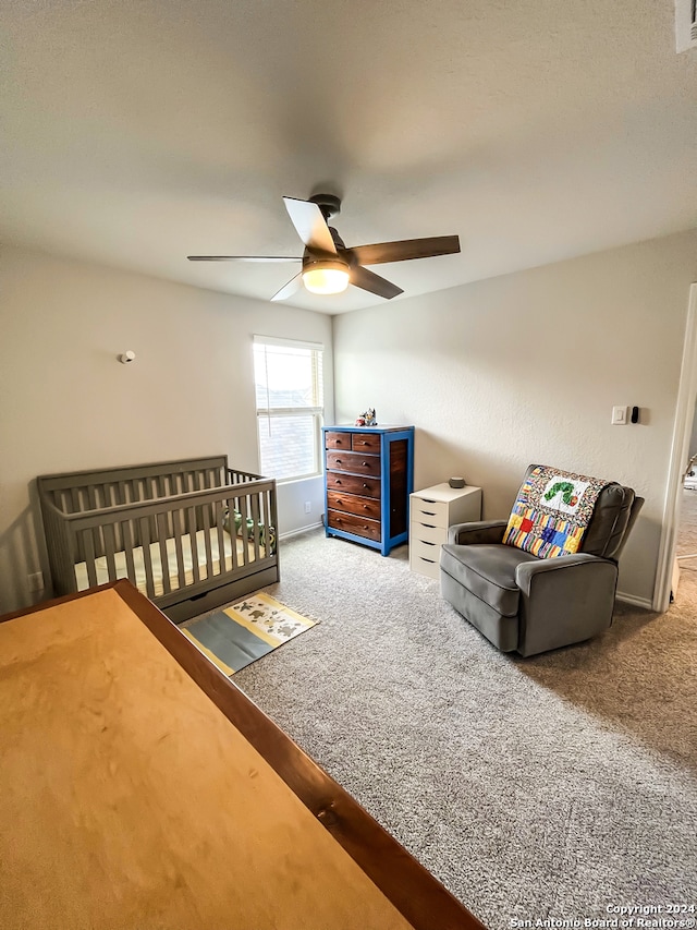 bedroom with carpet, a nursery area, and ceiling fan