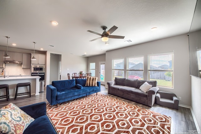 living room featuring hardwood / wood-style flooring, ceiling fan, and sink