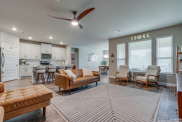 living room with ceiling fan and light wood-type flooring