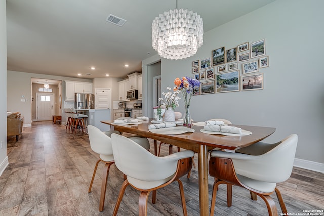 dining area with light wood-type flooring and a notable chandelier