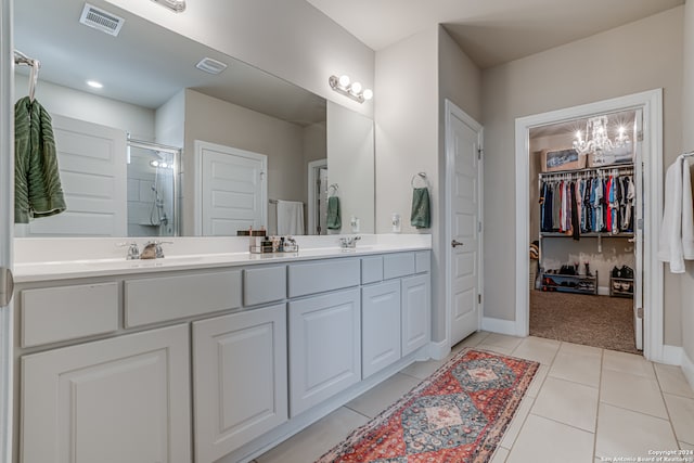 bathroom with tile patterned flooring, vanity, a chandelier, and a shower with door