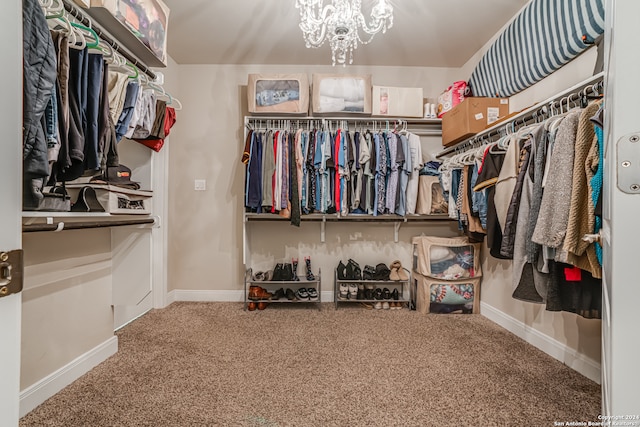 walk in closet with a notable chandelier and carpet