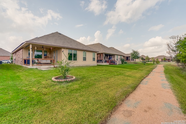 back of house with covered porch, ceiling fan, and a yard