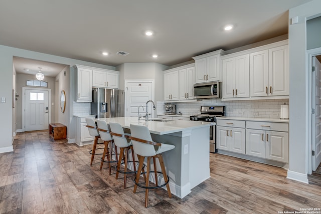 kitchen with appliances with stainless steel finishes, sink, light hardwood / wood-style floors, and white cabinets