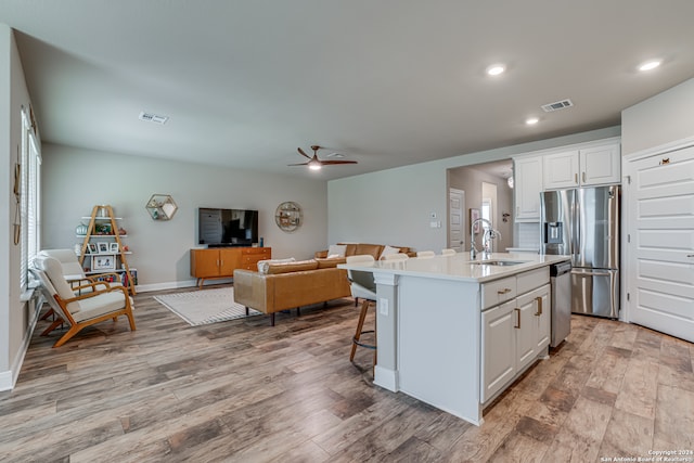 kitchen with white cabinetry, appliances with stainless steel finishes, an island with sink, and light wood-type flooring