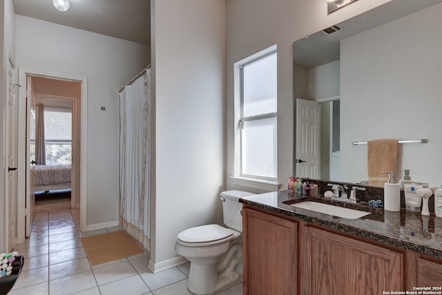 bathroom with toilet, vanity, and tile patterned flooring