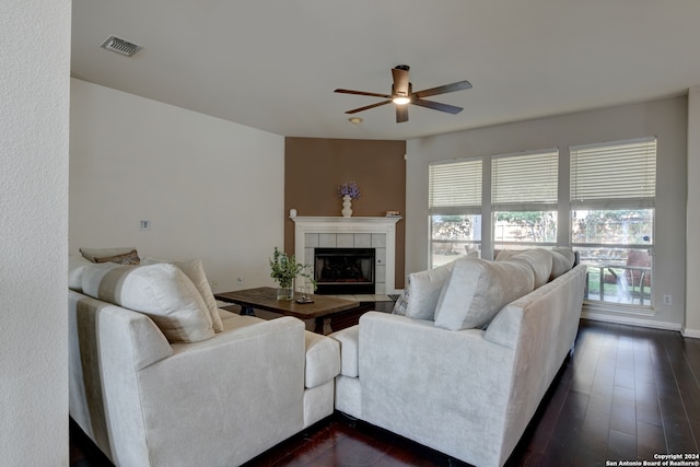 living room with dark wood-type flooring, ceiling fan, and a tile fireplace