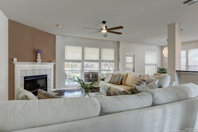 living room with ceiling fan, a tiled fireplace, and plenty of natural light