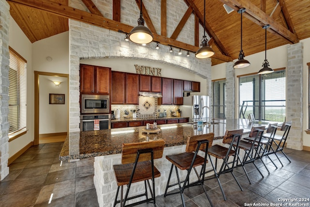 kitchen with high vaulted ceiling, appliances with stainless steel finishes, decorative light fixtures, and wooden ceiling